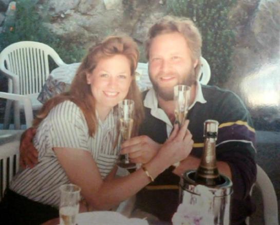Celebrating a special moment, the couple smiles while raising their champagne glasses together.