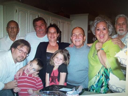 Friends and family members gather in a kitchen, sharing smiles and enjoying each other's company.
