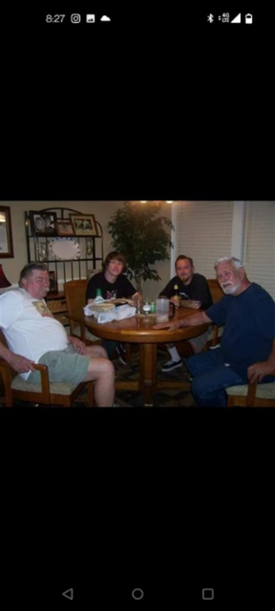 Four family members sit together at a dining table, enjoying each other's company and sharing food.