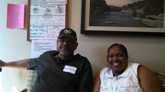 Two individuals smile together while sitting in a welcoming community space during a gathering.