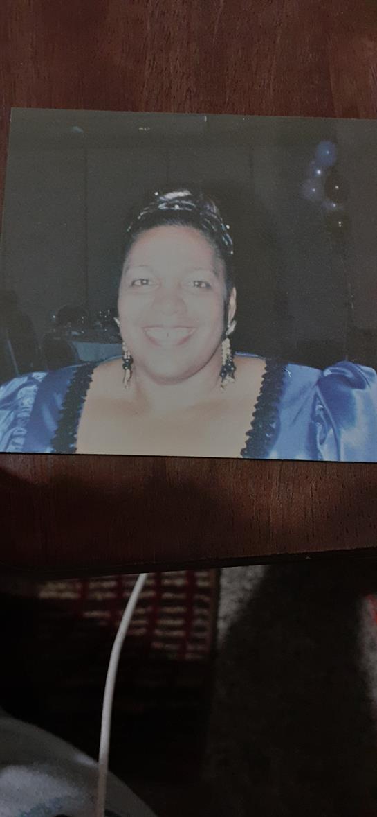 A joyful woman dressed in a blue outfit is enjoying a social event at night.