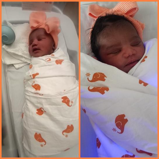 A newborn baby lies peacefully in a hospital wrapped in a cozy blanket with fish designs.