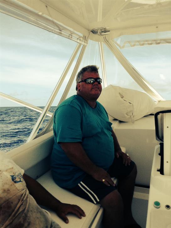 A man is sitting comfortably on a fishing boat, enjoying the ocean breeze and waves.