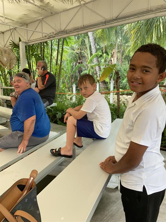 A group of children and adults are seated outdoors, enjoying a quiet moment in nature.