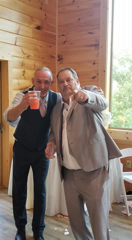 Two men raise their drinks and enjoy a festive moment together in a cozy wooden setting.