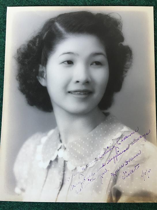 Young woman smiles while wearing a vintage dress with a collar, captured in black and white.