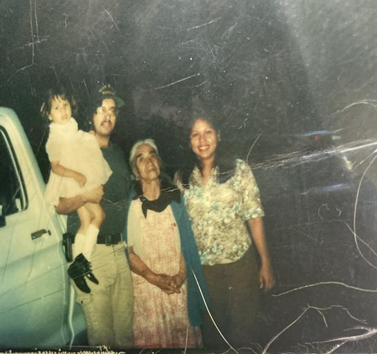 Four family members pose together at night near a pick-up truck, showcasing a warm bond.