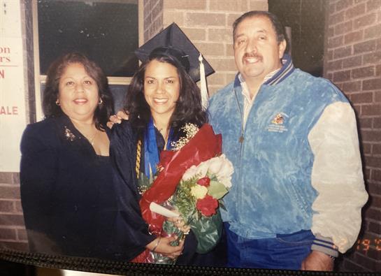 Family members celebrate a graduation with flowers and smiles at a school location.