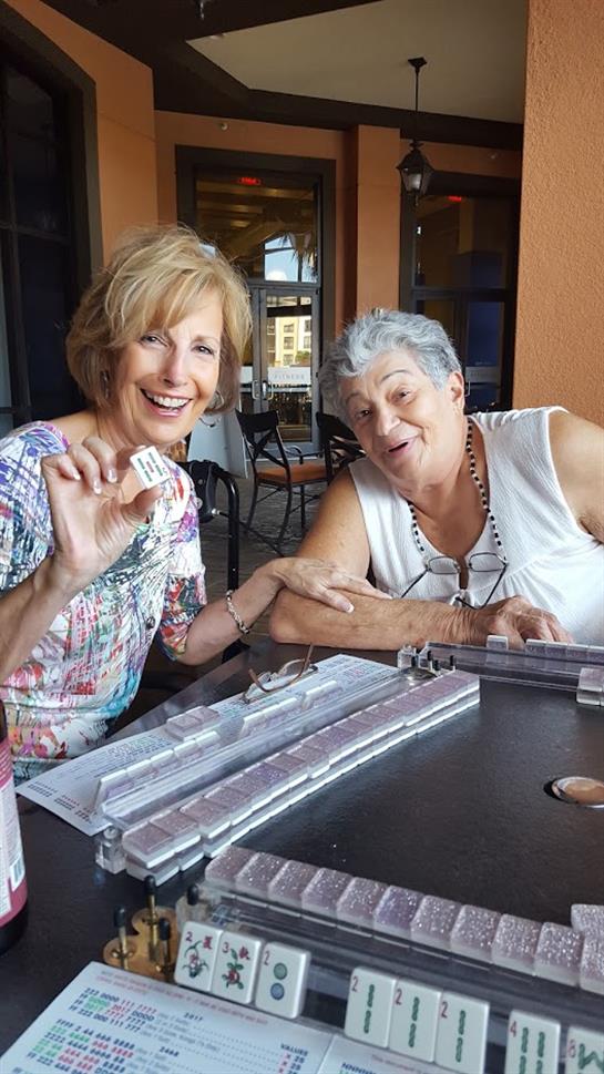 Two women laugh and share a joyful moment at a cafe while playing games on the table.