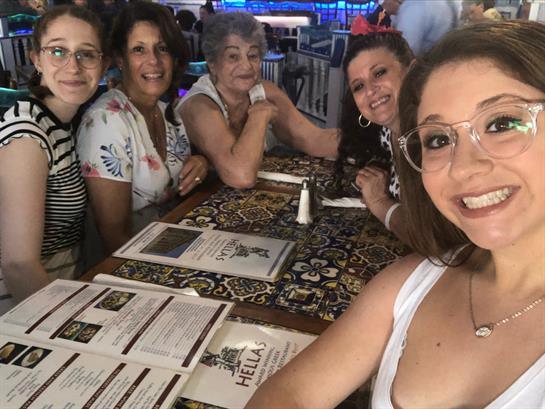 Friends gather around a table chatting and smiling while enjoying their lunch at a restaurant.