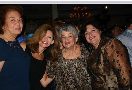 A group of four women smile and pose together, celebrating friendship in a cheerful atmosphere.