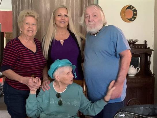 Four adults share laughter in a cozy living room during a family gathering.