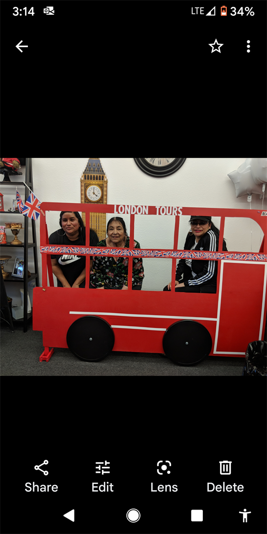 Group of three women pose inside a colorful London bus decoration, smiling joyfully at an event.