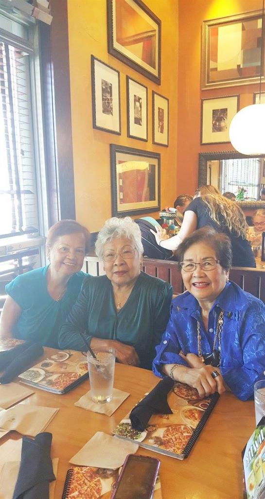 Three smiling elderly women sit together at a table, enjoying each other's company during brunch.