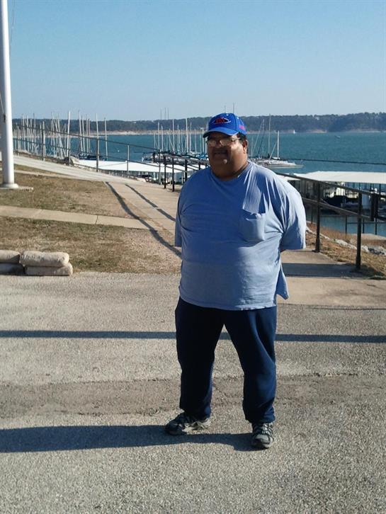 Individual enjoys a calm day at a marina, surrounded by boats and clear blue waters.