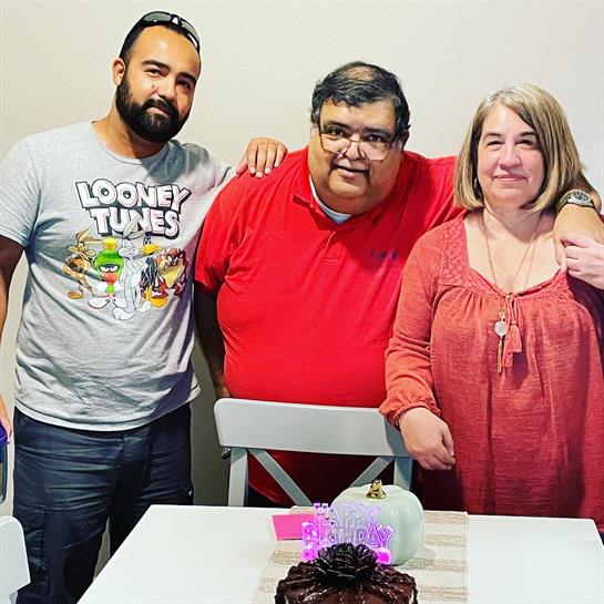 Three friends gather around a birthday cake, smiling and enjoying a joyful celebration at home.