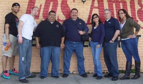 Five friends gather in front of a colorful mural in Los Angeles, enjoying their time together.