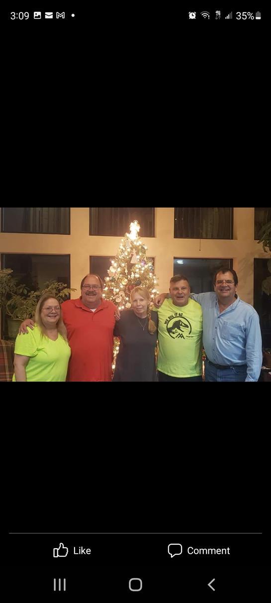 Five family members celebrate together by a beautifully decorated Christmas tree in a warm setting.