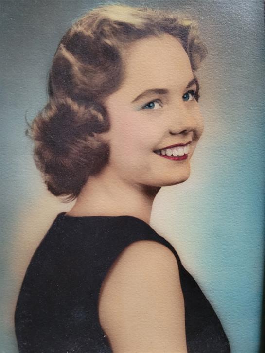 A cheerful young woman showcases vintage fashion and joyful expression against a gentle background.