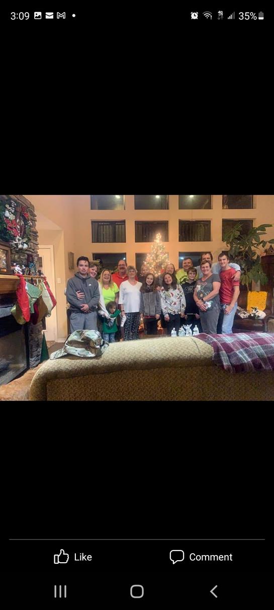 Friends and family gather in a spacious living room adorned with holiday decorations and a tree.