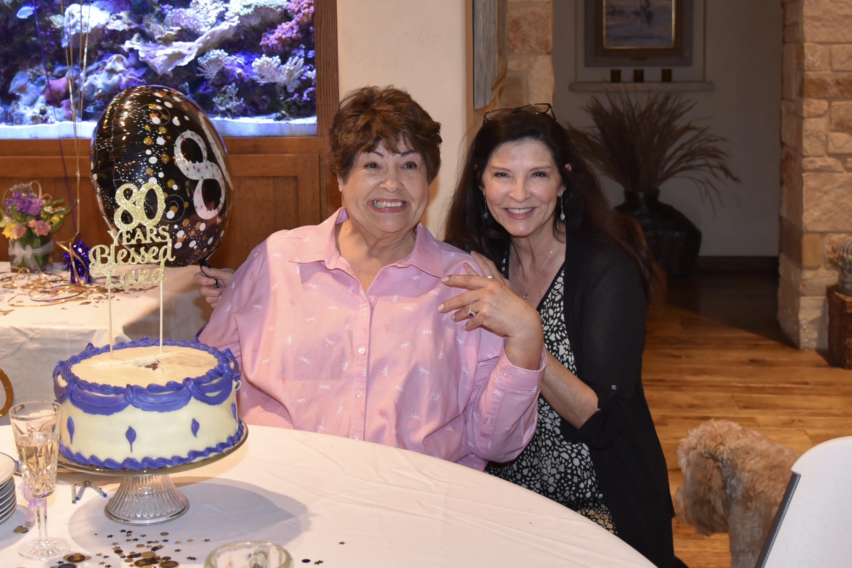 Two women sitting at a table with a cake