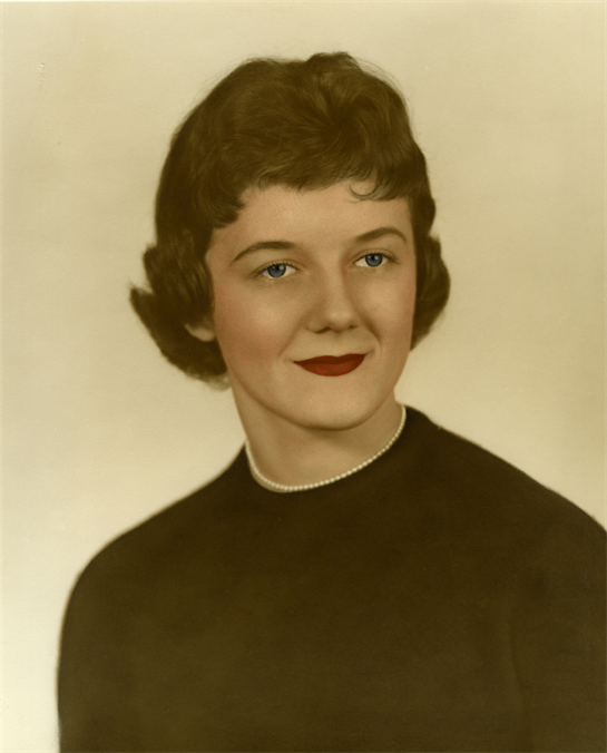 Young woman with curly hair wearing a black top and necklace poses for a timeless portrait.