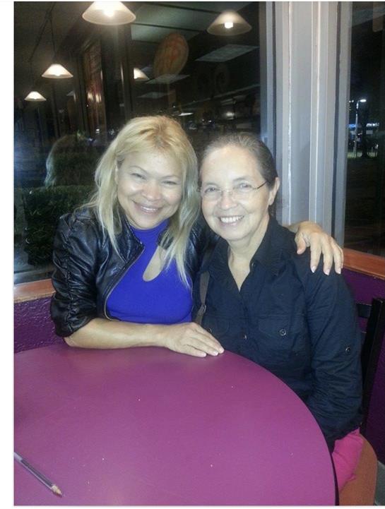 Two friends sit happily at a circular table, enjoying their time together in a warm cafe setting.