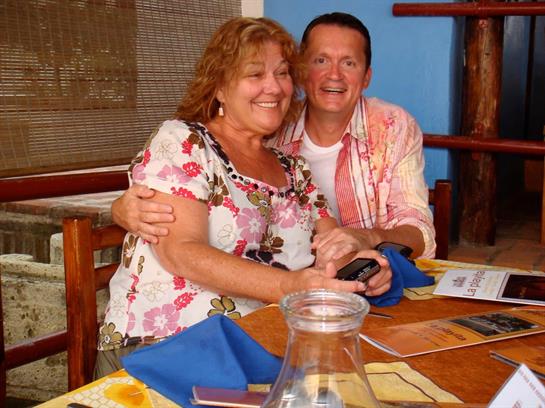 Two friends share laughter and smiles at a beachside restaurant during dinner time.