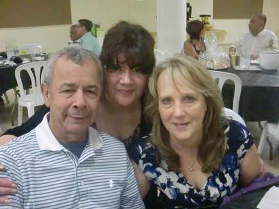 Three friends gather closely, smiling and enjoying each other's company at a lively event.