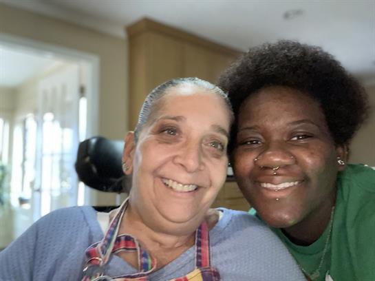 Two women happily pose together, enjoying companionship in a warm and inviting setting.