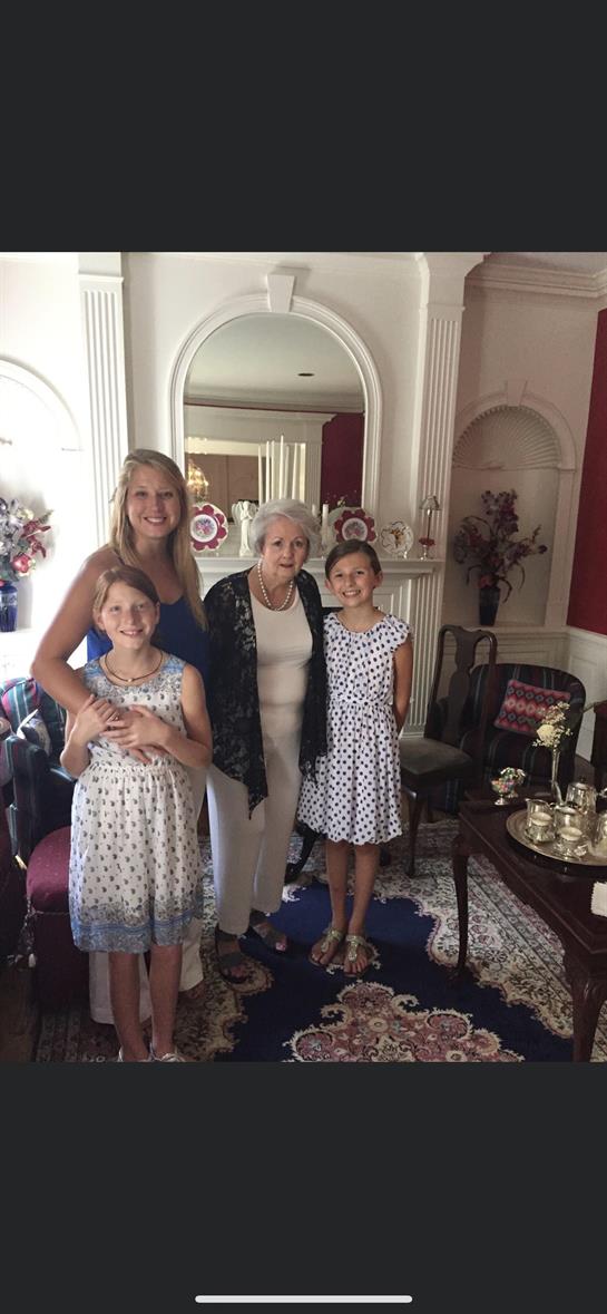 Three generations of women smile together in a decorated living room during a family visit.