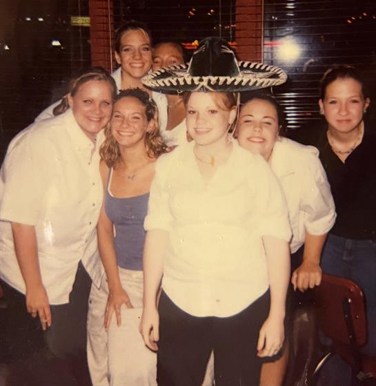 Friends enjoying a lively indoor celebration, one wears a sombrero while others pose happily.