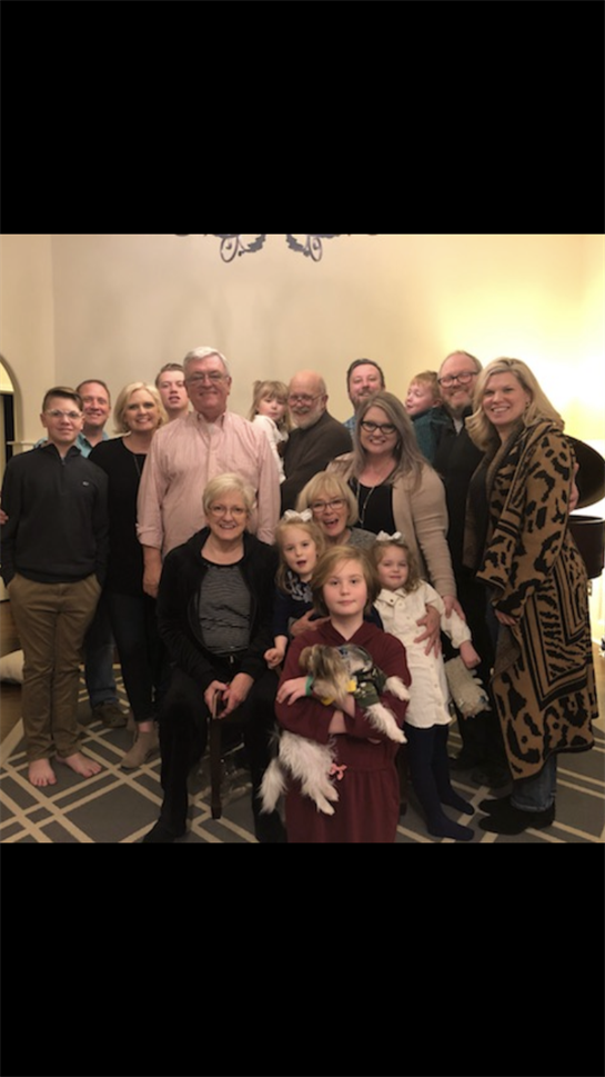 A group of family members poses together in a living room, celebrating a winter holiday with warmth.
