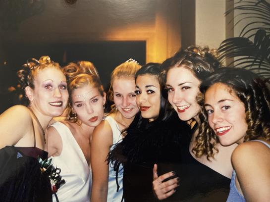 A group of friends dressed in elegant outfits is enjoying a joyful celebration together.