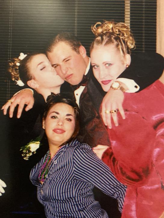 Four friends pose closely together, showcasing their unique styles and playful interactions.