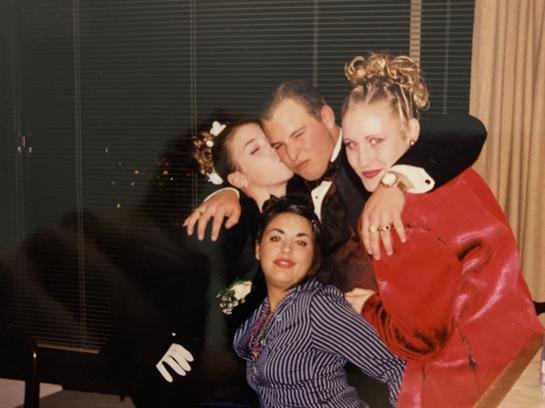 Four friends enjoy a joyful moment at a formal gathering, showcasing laughter and closeness.