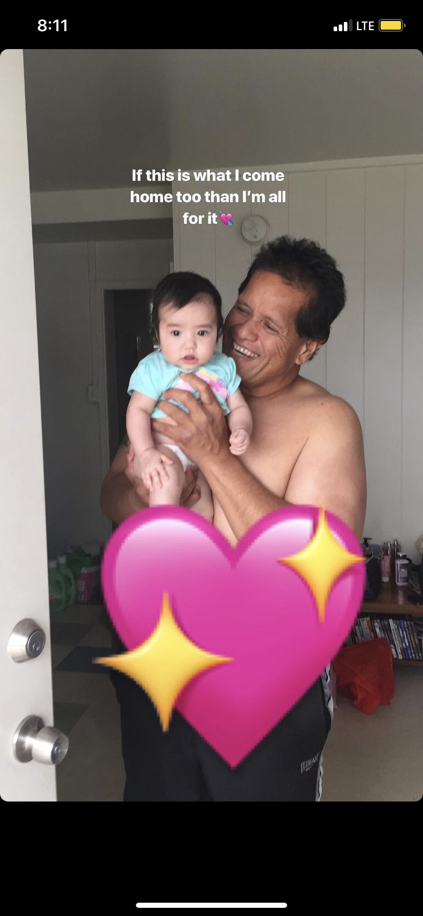 A proud parent joyfully holds a baby at the entrance of their home, radiating happiness.
