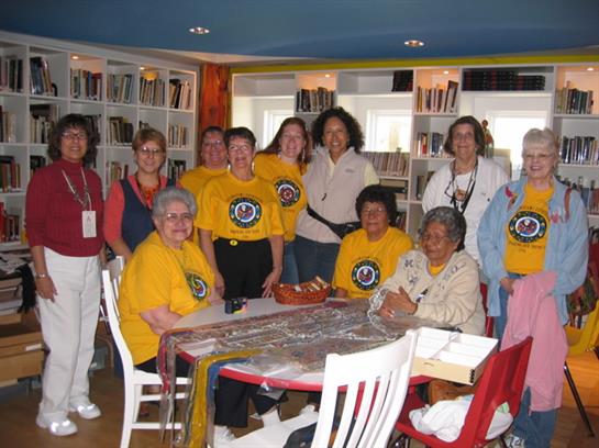 Ten volunteers in yellow shirts gather at a community center, smiling and promoting teamwork.