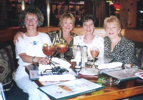 Four women share drinks and menus, celebrating friendship and laughter at a table.