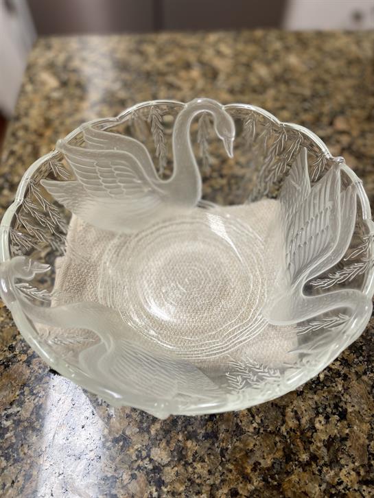 Delicate glass bowl with detailed swan motifs resting on a textured granite background.