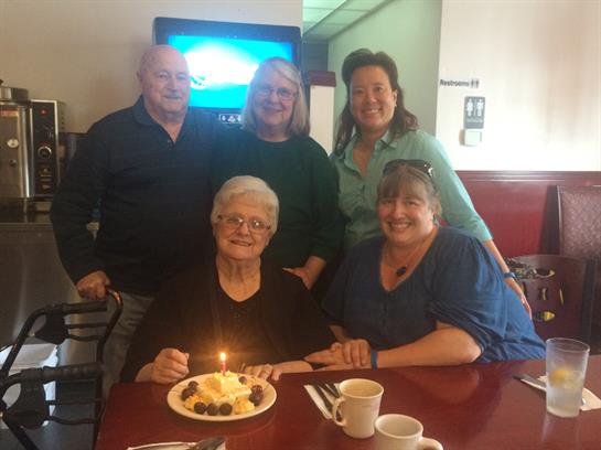 A joyful family gathering at a restaurant to celebrate a special occasion with cake and smiles.