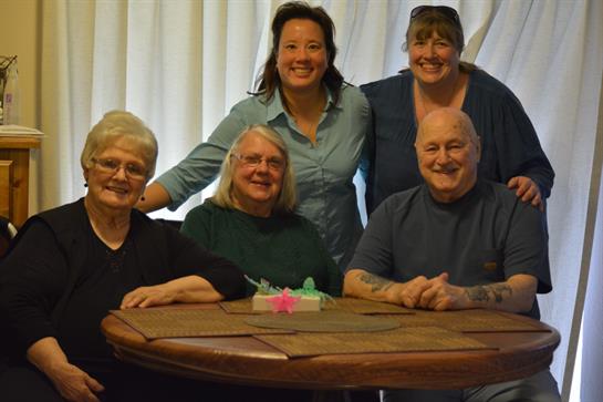 Five friends gather around a wooden table, sharing laughter and enjoying games in a warm atmosphere.