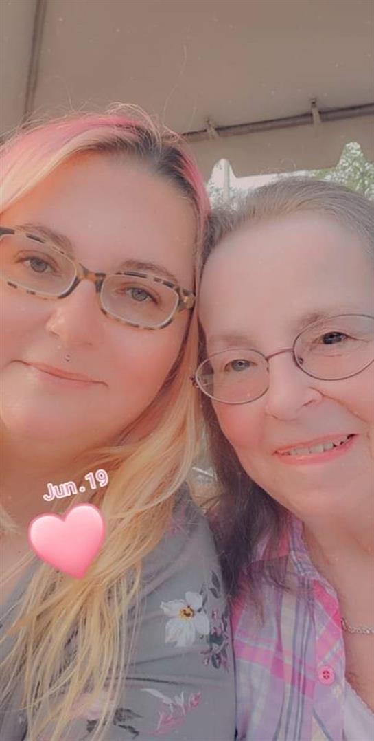 Two women smile together, enjoying a sunny day in June, capturing a moment of happiness outdoors.