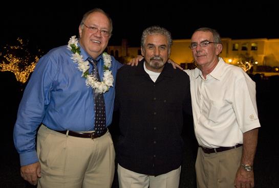 Three friends gather for a joyful moment at a celebration in Hawaii during the evening hours.