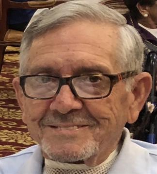 Elderly man with glasses enjoys a joyful moment at a gathering in a comfortable location.