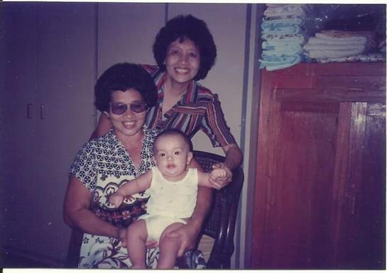 Two women and a baby enjoy a joyful moment together in a warm indoor atmosphere.