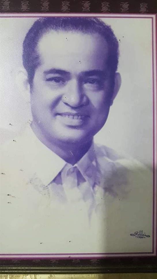 A man with a friendly smile poses for a classic portrait wearing a formal white shirt.