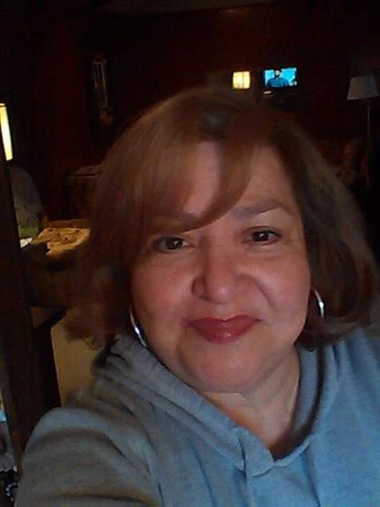 A cheerful woman poses happily in a cozy cafe, enjoying her time with friends nearby.