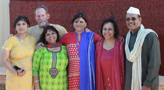 Friends dressed in colorful traditional attire enjoy a joyful moment together at a festive event.