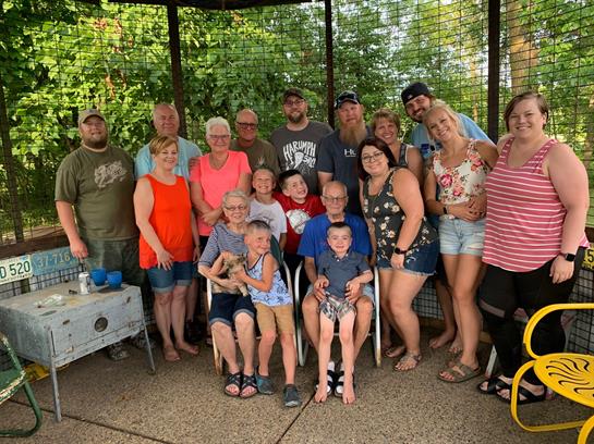 Family members come together in a gazebo during a summer picnic, enjoying a joyful reunion.